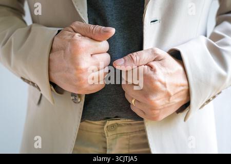 Businessman with hands straightening his blazer or jacket. Front view, close up shot. Stock Photo