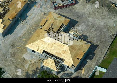 Aerial view of builders working on unfinished residential house with wooden roof frame structure under construction in Florida suburban area. Stock Photo