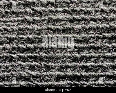 Extreme close-up of a black textured fabric, revealing a horizontal ribbed pattern with visible, fuzzy wool fibers in a detailed macro view. Stock Photo