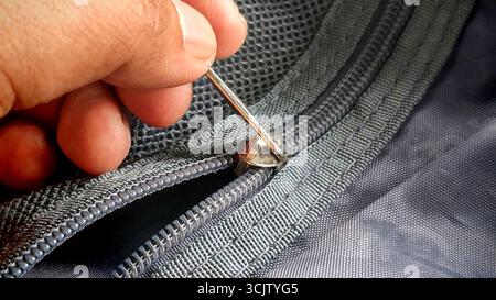 Person's Hand Aligning a Zipper on a Backpack Stock Photo