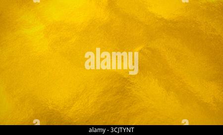 Metallic yellow gold foil paper texture, abstract festive vibrant background Stock Photo