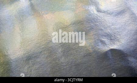 Iridescent silver foil paper texture, abstract festive background with pastel colors Stock Photo