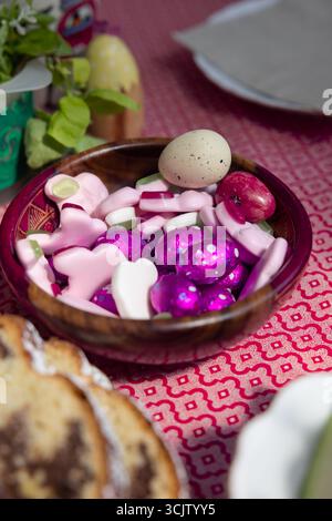 chocolate easter eggs wrapped in violet foil, and various sweets and gummy bears cozonac sweet bread on the side Stock Photo