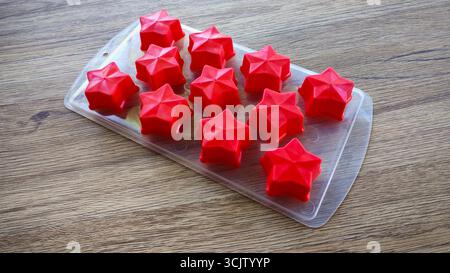 Empty red silicone star molds in a transparent tray on a wooden table Stock Photo