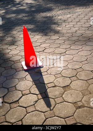 An eye-catching cone sign stands on the concrete block sidewalk. Stock Photo