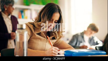 Girl, students and writing notes in classroom for education, lesson revision and quiz. Learner, teenager and learning for high school assignment Stock Photo