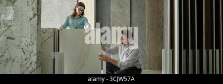 Young Caucasian Woman and Young Caucasian Man Examining Marble Slab Samples Stock Photo