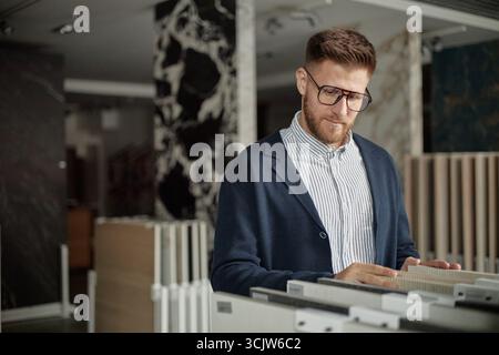 Caucasian Young Adult Man Examining Samples in Modern Showroom Stock Photo