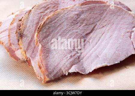 Cooked roast crumbled ham slices on a brown paper background backdrop. Stock Photo
