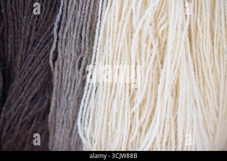 Bundles of natural wool yarn in brown, gray, and cream colors with visible twisted strands and detailed fiber texture. Stock Photo