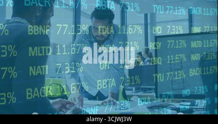 Examining Middle Eastern man wearing button-up shirt leaning on desk in office, with documents Stock Photo