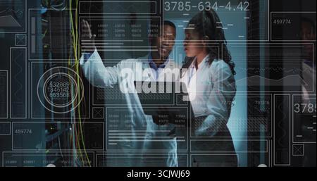 Examining labcoat technicians adjusting cables and monitoring overlays in data center server racks Stock Photo