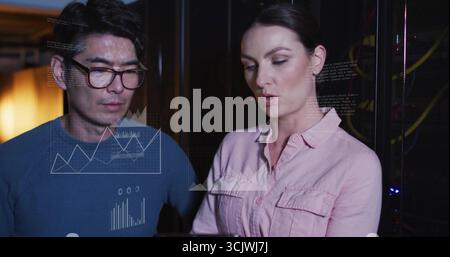 Analyzing data overlays, two IT professionals working in server room, with racks and cables Stock Photo