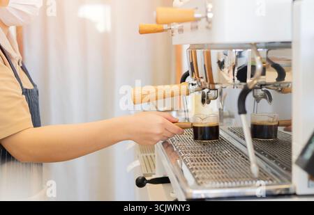Side view shot of female barista making coffee or preparing an espresso for customers at the bar. Making coffee concept. Selective focus. Stock Photo
