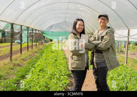 Smart couple entrepreneur standing in thier small business hydroponic greenhouse with copy sapce. Stock Photo