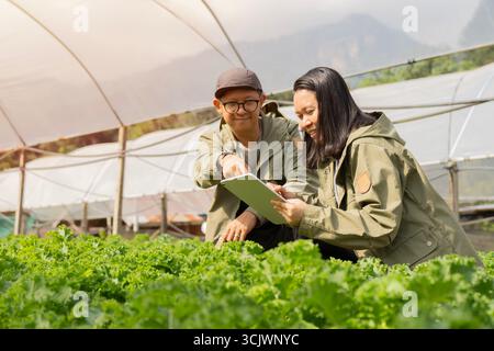 Two agricultural engineers working by smart tablet In the industrial greenhouse. Test Plants Health Concept. Selective focus. Stock Photo