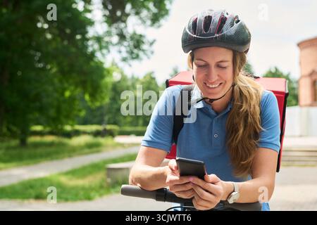 Woman Smiling While Using Smartphone Outdoors Stock Photo