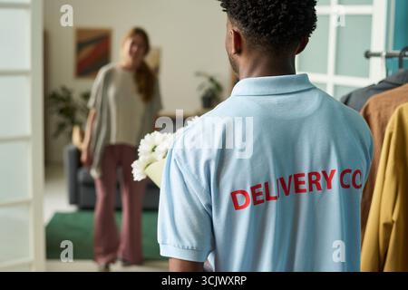 Black Man Delivering Flowers to Woman at Home Stock Photo