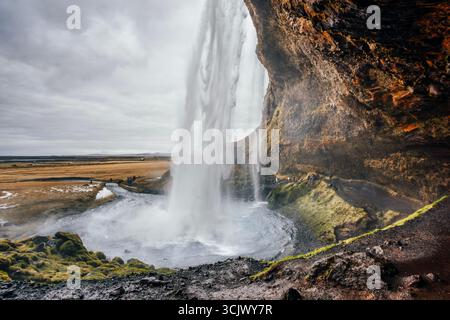Spectacular View From Behind Seljalandsfoss Waterfall in Iceland With Moss Covered Rocks. Icelandic cascade, volcanic landscape, South Coast attractio Stock Photo