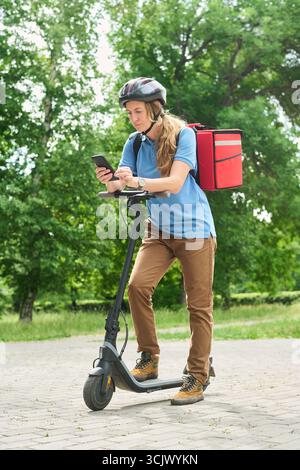 Woman Standing on Electric Scooter Checking Smartphone Stock Photo
