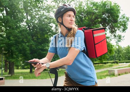 Woman Delivering Food by Scooter and Using Digital Tablet Stock Photo