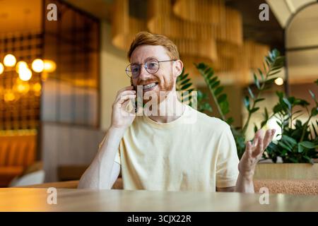 Bearded redhead man holding phone to ear at restaurant Stock Photo