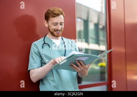 Man doctor reviewing documents in open folder outdoors Stock Photo
