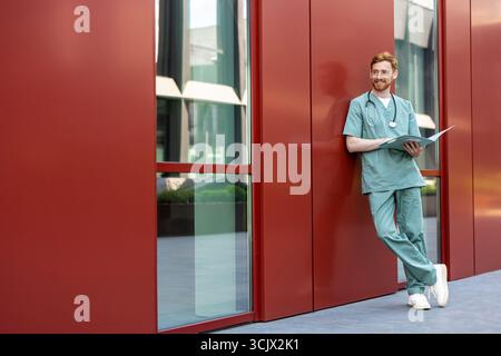 Man doctor in scrubs outdoors with open records folder Stock Photo