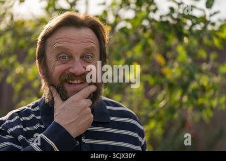 Portrait of a thinking or surprised senior man. Elderly bearded caucasian male in nature. Face bearded male dreams of solving issues, close up Stock Photo
