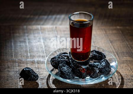 Homemade dark damson plum brandy in glasses on a wooden table, close up. Drink from dry plums Stock Photo