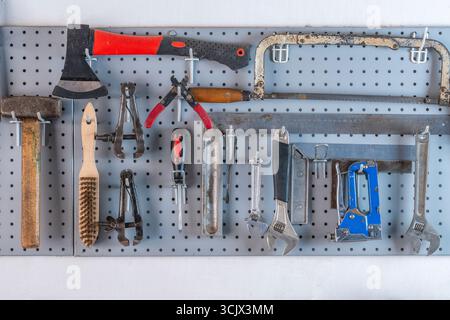 Work tools hanging on steel wall as background in workshop, close up Stock Photo