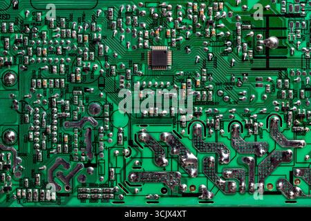 Green printed circuit board with radio components on background. Vintage circuit board with soldering trace, parts and microcircuits, close up, top vi Stock Photo