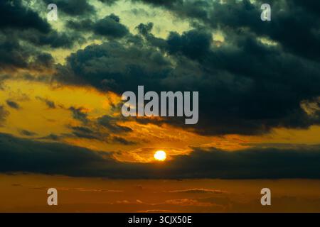 Dark dramatic horizon sky during sunset. Black clouds and setting sun. Evening sunshine background Stock Photo