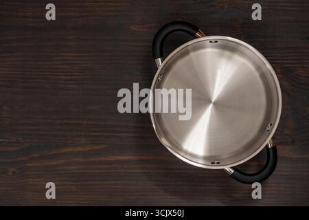 Stainless steel cooking pot on wooden background, close up, top view, copy space Stock Photo