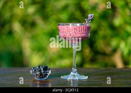 Fresh blueberry smoothie in vintage crystal glass against summer garden background on wooden table, close up. Concept of healthy eating. Smoothies fro Stock Photo