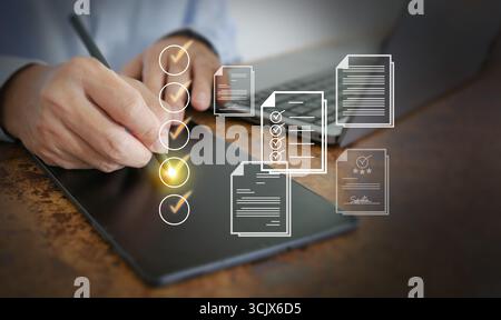 Hand writing checklist on digital tablet with laptop, illustrating project management, quality control, and productivity strategy for corporate and pr Stock Photo