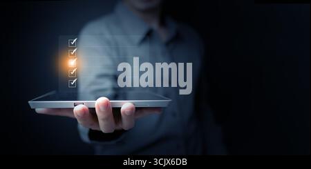 Hand holding tablet with checklist interface, illustrating digital business planning, corporate organization, and task management strategy for product Stock Photo