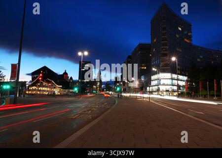 The Srand in Liverpool at dusk with light trails, modern buildings, and skyline under deep blue evening sky. Stock Photo