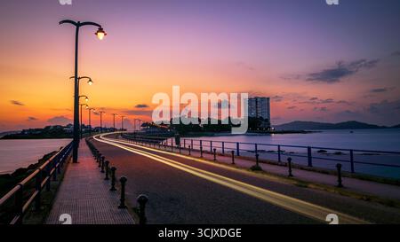 A long exposure shot captures the stunning view of the bridge connecting the island of Toralla to the mainland. The sky is a beautiful blend of orange Stock Photo