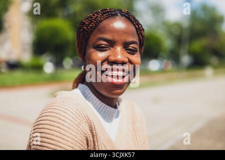 Close up portrait of cheerful young African American woman with braces, smiling brightly on a sunny day. Stock Photo