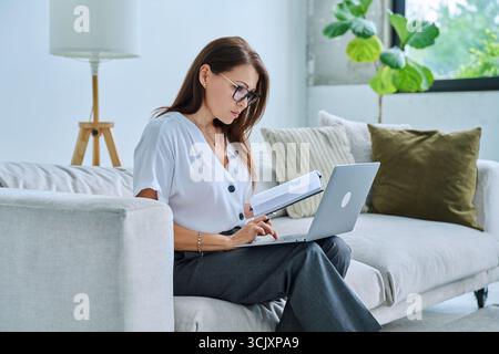 Middle aged serious woman working on c with laptop notepad Stock Photo