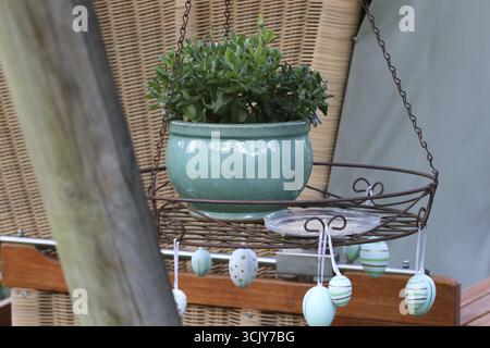 A planter in a hanging tray, in front of a beach chair, decorated with Easter eggs. Bielefeld, Germany Stock Photo
