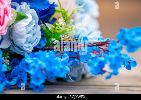 Wedding rings nestled among a vibrant blue and white bridal bouquet Stock Photo