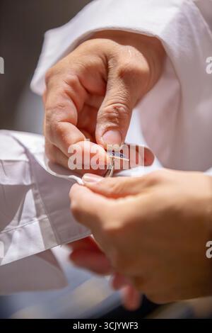 Best man carefully attaching cufflinks for the Groom Stock Photo