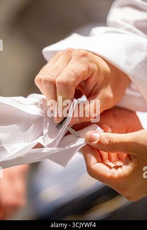 Best man carefully attaching cufflinks for the Groom Stock Photo