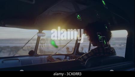 Steering man in green plaid shirt driving camper van on coastal road with dreamcatcher, copy space Stock Photo