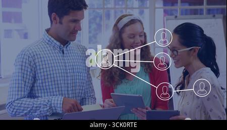 Collaborating three professionals holding laptop and tablets in office space, whiteboard background Stock Photo