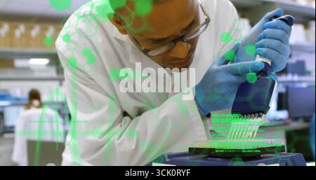 Pipetting technician wearing glasses loading 96-well microplate at lab bench with pipette Stock Photo