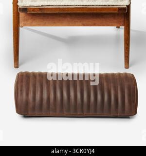 Brown leather bolster pillow resting on floor beneath wooden bench Stock Photo