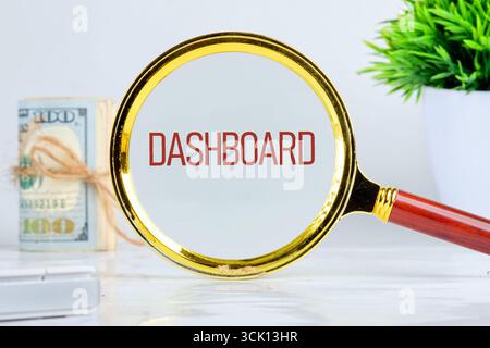 DASHBOARD word showed through a magnifying glass on a light background. Analyst working with Financial Report and Business Analytics concept. Stock Photo